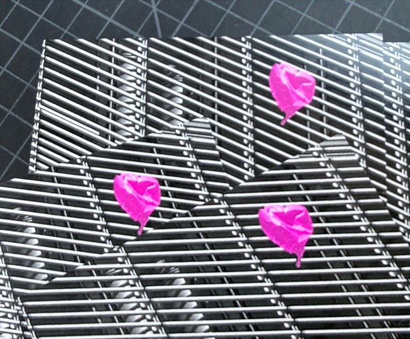 Fluorescent pink hearts over silver grid zine covers