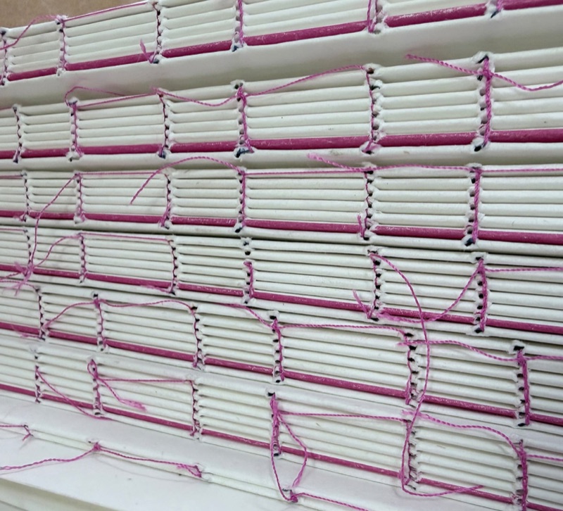 Smyth-sewn book blocks stacked with pink thread
