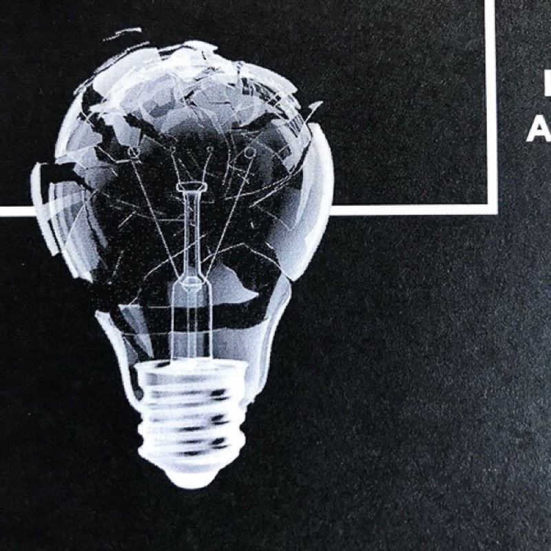 White ink halftone lightbulb on black paper